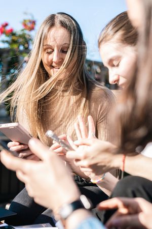 College students taking a break from studying showing messages on phones while talking and laughing.