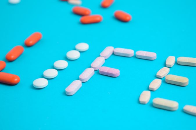 Close up of various pills making the word "LIFE" on blue table