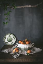 Orange tangerines in ceramic ornamental bowl on wooden table