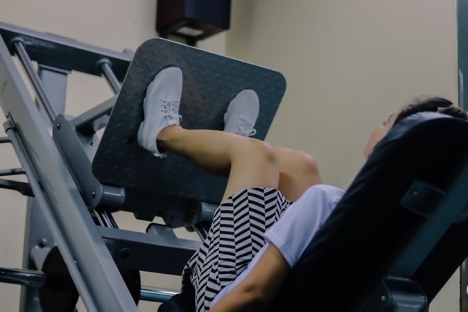 woman using leg press machine in gym.
