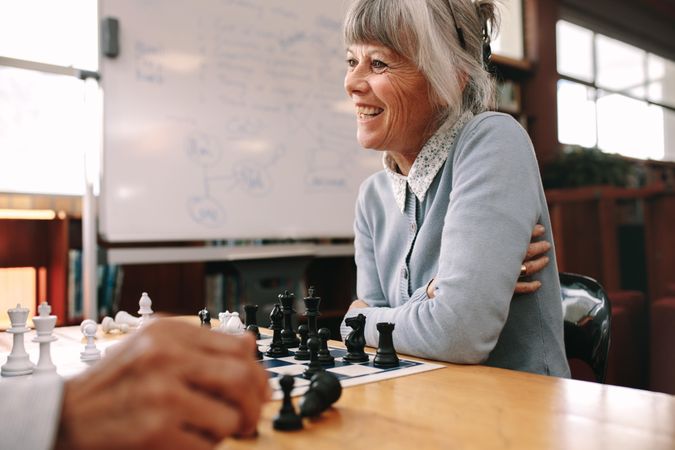 Close up of a woman sitting in classroom and playing chess with a colleague