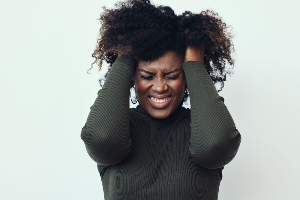 Black woman with her hands in her hair expressing annoyance