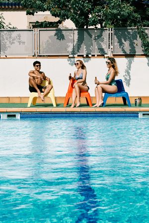 two young and women looking at a handsome man by the pool