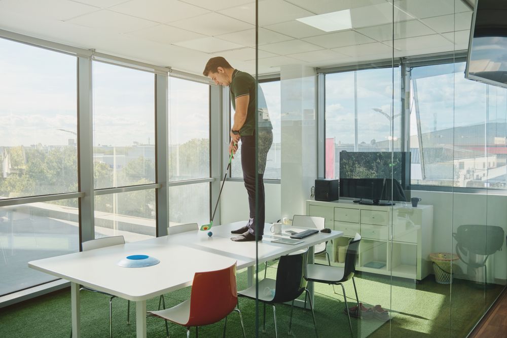 Man playing golf on table in office