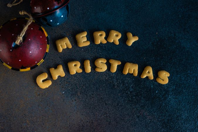 "Merry Christmas" written on dark table with ornaments