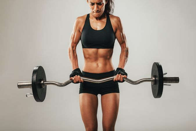 Muscles buldging on arms of woman using barbell