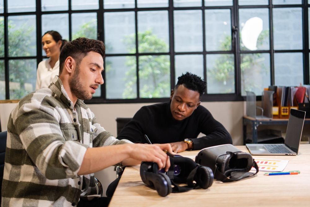 Two male colleagues working on desk with VR headsets