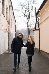 Smiling couple holding hands on street with fairy lights hanging on buildings