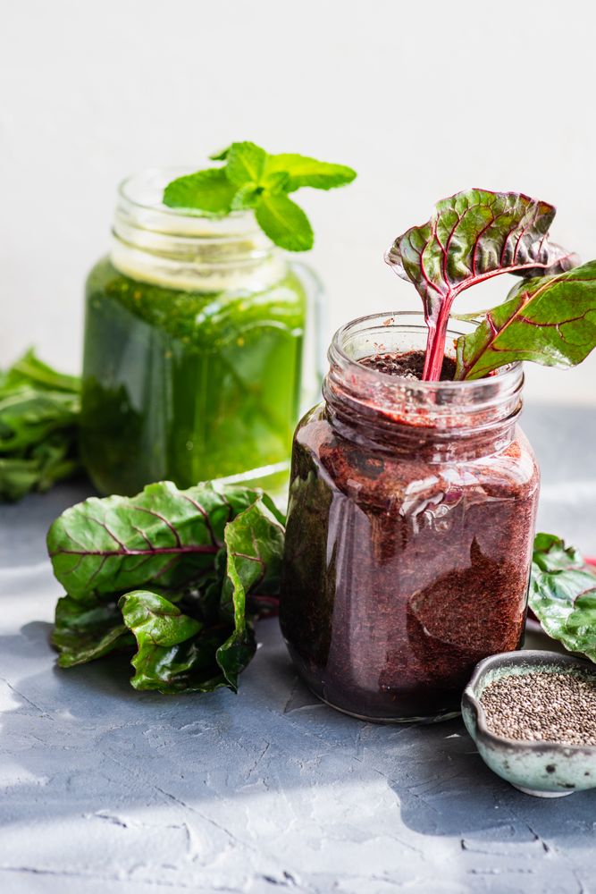 Two smoothies one beet and green on counter with copy space