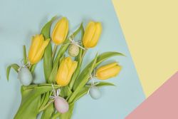 Fresh yellow flowers and easter eggs with green leaves