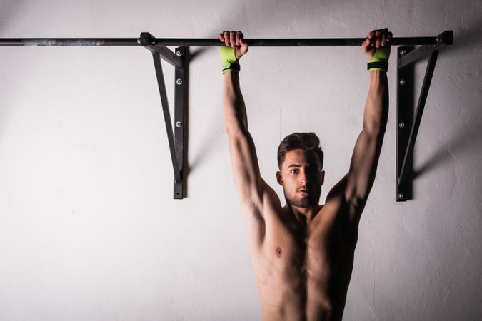 Man hanging on bar near wall in gym