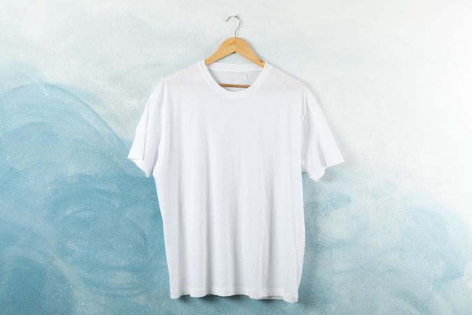 Hanger with blank plain t-shirt on blue background, space for text