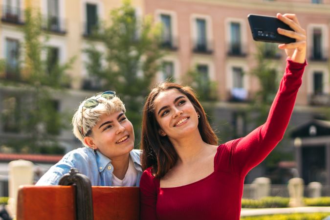 two women taking a selfie sitting on a bench