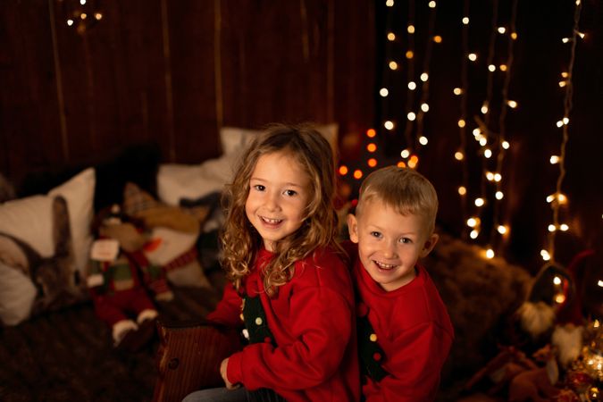 Siblings sitting in wooden horse swing during christmas