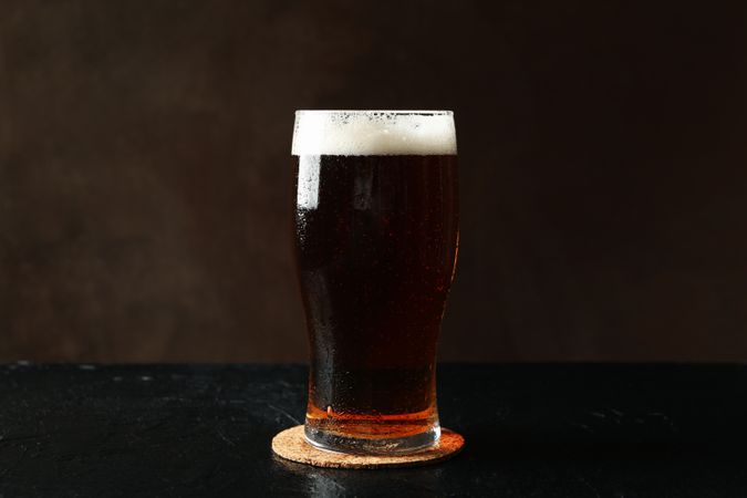 Glass of beer on table against brown background
