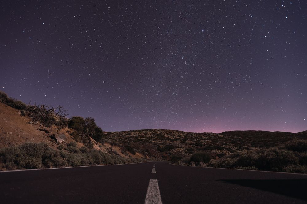 Empty road at night under bright stars