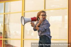 Woman yelling into megaphone in checkered shirt 43Lqxb