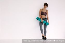 Woman standing with yoga mat in studio 48B7zJ