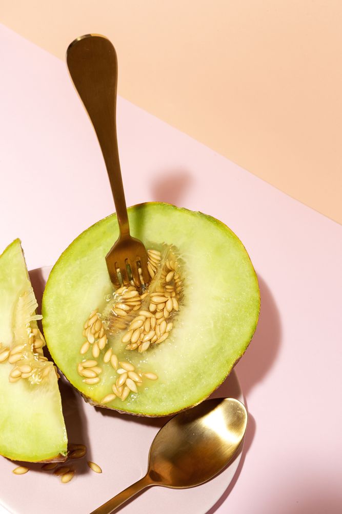 Sliced small melon on plate with spoon and fork