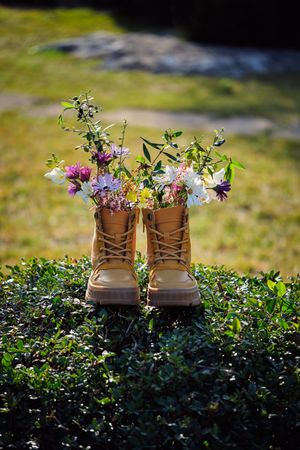 Boots with flowers on green hedge