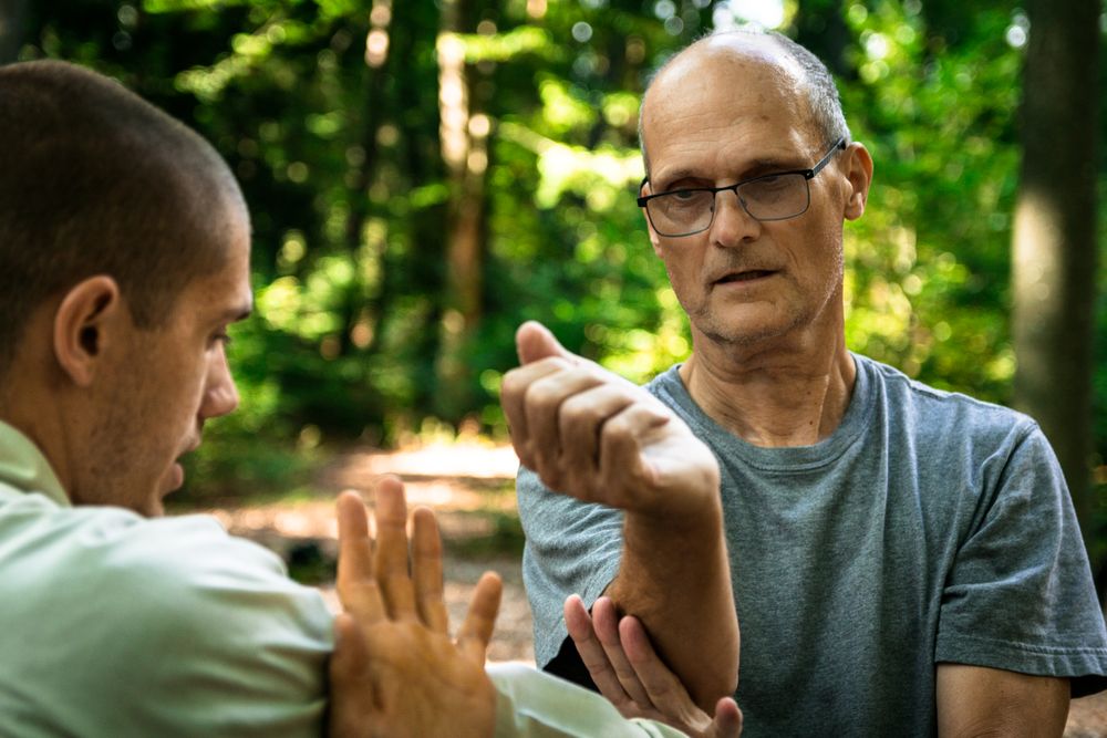 Older man training martial arts student in forest