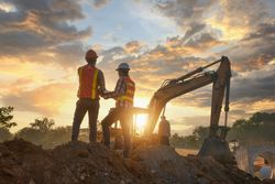 Two men with bump caps standing at the construction site