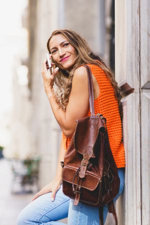 Woman waiting on the street leaning on urban facade