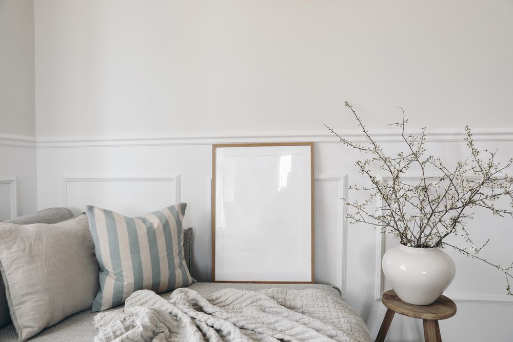 Neutral living room with vase, blooming cherry plum tree branches with mockup poster