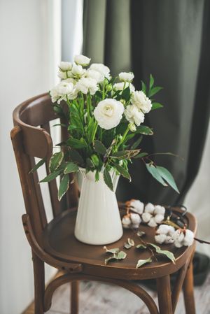 Spring buttercup flowers in enamel jug on chair