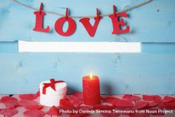 Gift box and the word love spelled out in paper letters hanging on twine with a candle in front 5pyjv4