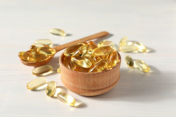 Omega pills in a wooden bowl on a plain background
