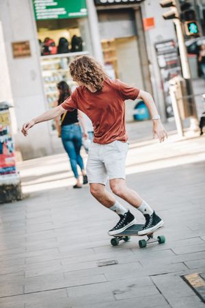 Confident man riding longboard across city street