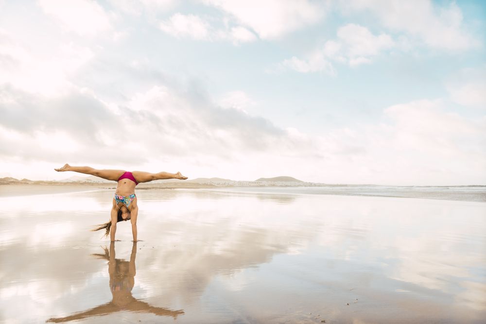 Woman doing handstand near sea