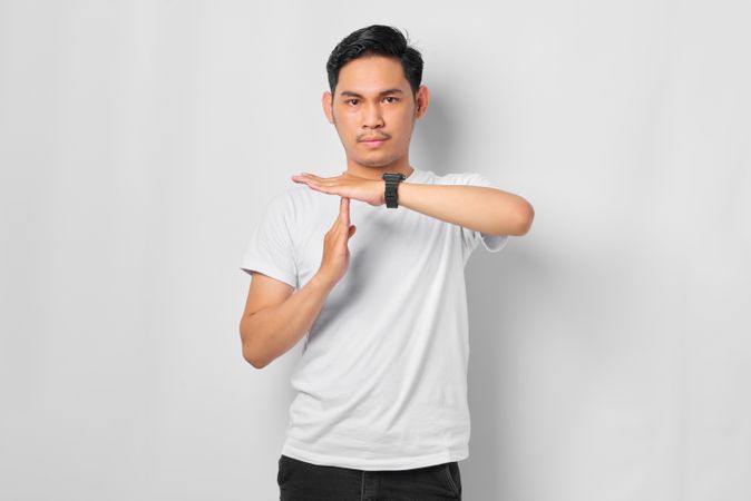 Asian male in grey studio making “time out” gesture