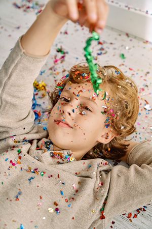 Boy covered with confetti lying on floor