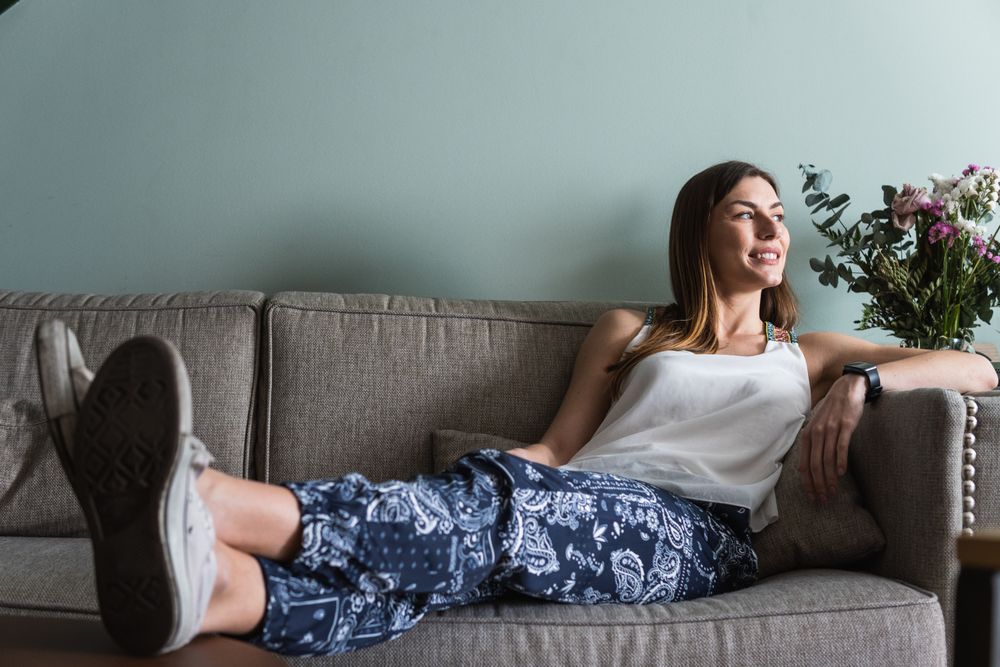 Dreamy woman resting on sofa in house