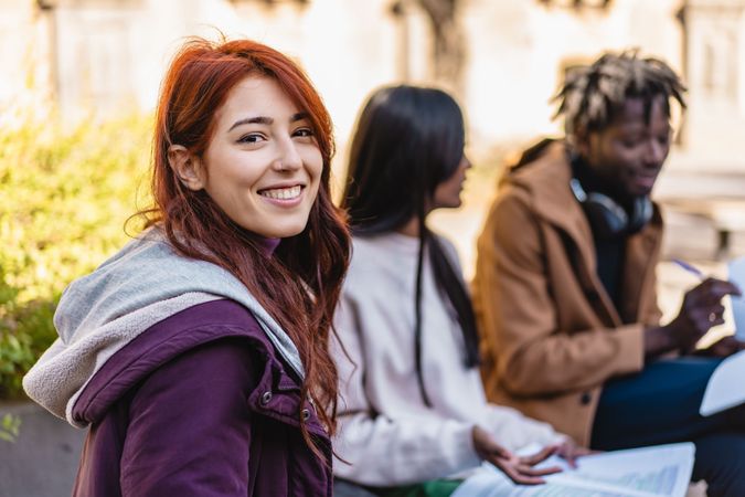A smiling student with her friends in background studying
