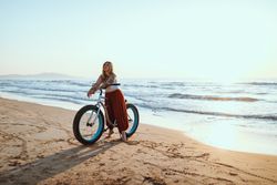 Joyful woman riding bicycle along peaceful beach