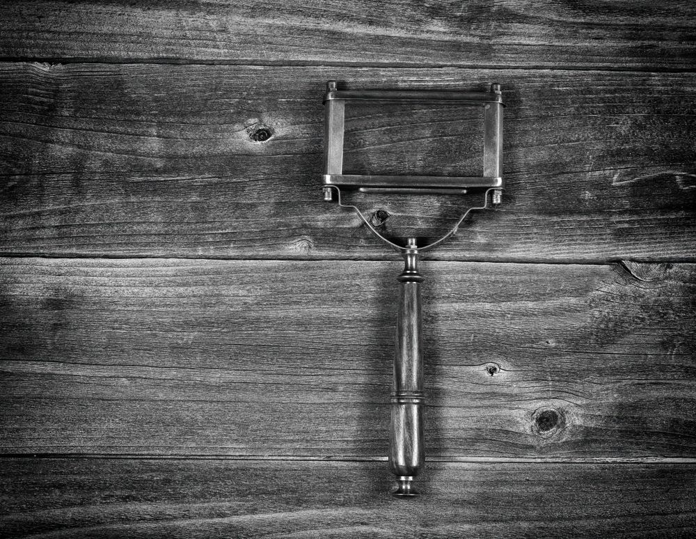 Old magnifying glass on rustic wood table in monochrome