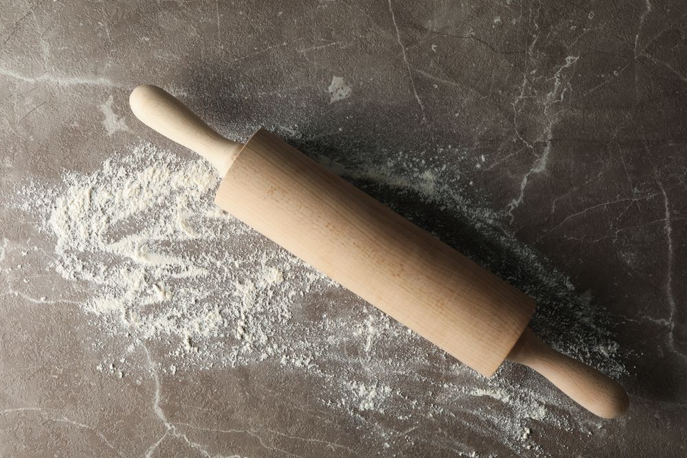 Rolling pin and flour on gray background, top view