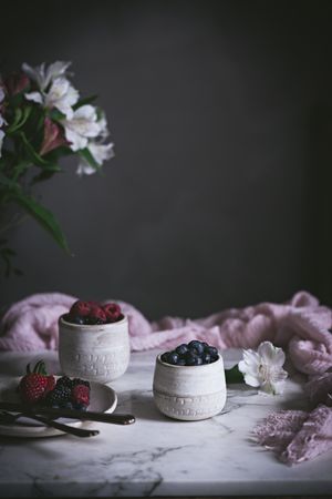 Raspberries and blueberries on glasses on table