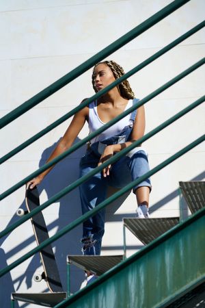 Female standing on green stairs with skateboard