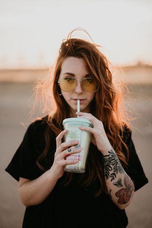 Long haired person drinking milkshake and looking at camera