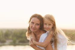 Little girl on mother’s back with beautiful scenery in background