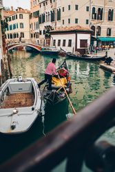 Man in boat floating in canal between buildings