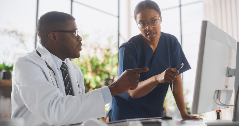 Doctor's Office: Physician Talks With Professional Head Nurse, Using Computer.