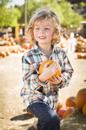 Boy Holding His Pumpkin at a Pumpkin Patch Outdoors