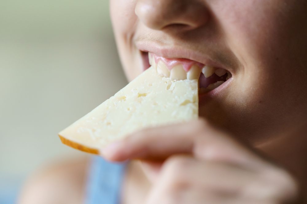 Girl biting into cheese slice