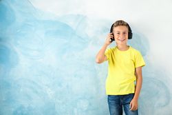 Boy with headphones against color background, space for text