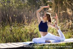 Female wearing sport clothes doing advanced pigeon yoga pose outside 488274